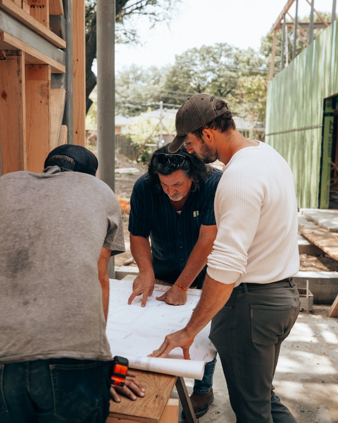 Drie mannen die op een werf samen plannen bekijken op een werktafel